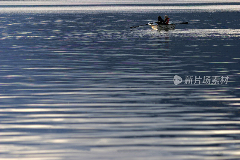 两个人划着小船在水面上。
