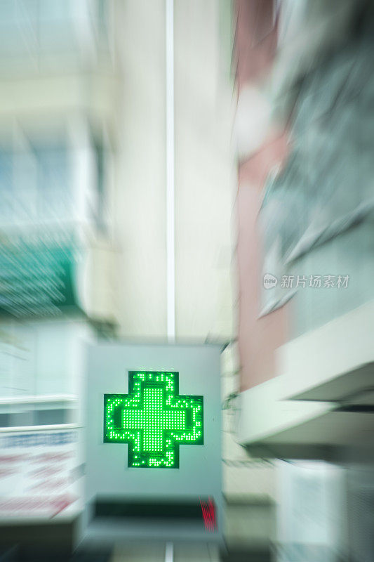 药店绿十字标志位于某城市街道、住宅楼内。