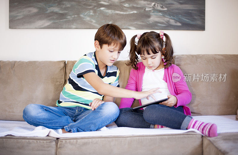 男孩和女孩在客厅里玩平板电脑，