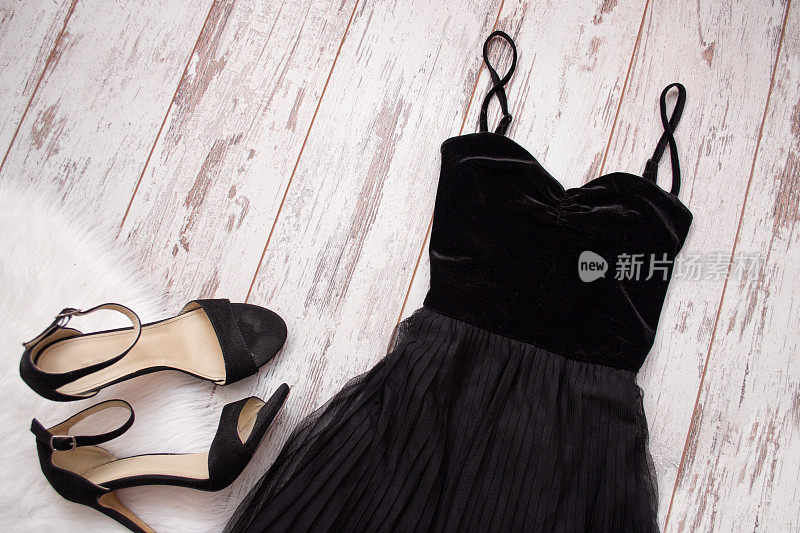 木制背景上的黑色晚礼服和鞋子。时尚的概念。俯视图，文本空间