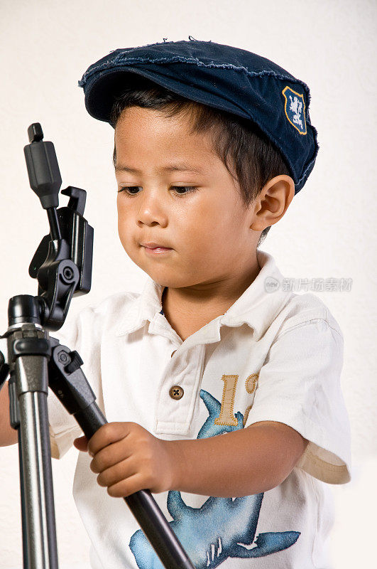 亚洲男孩与相机三脚架和酷帽子