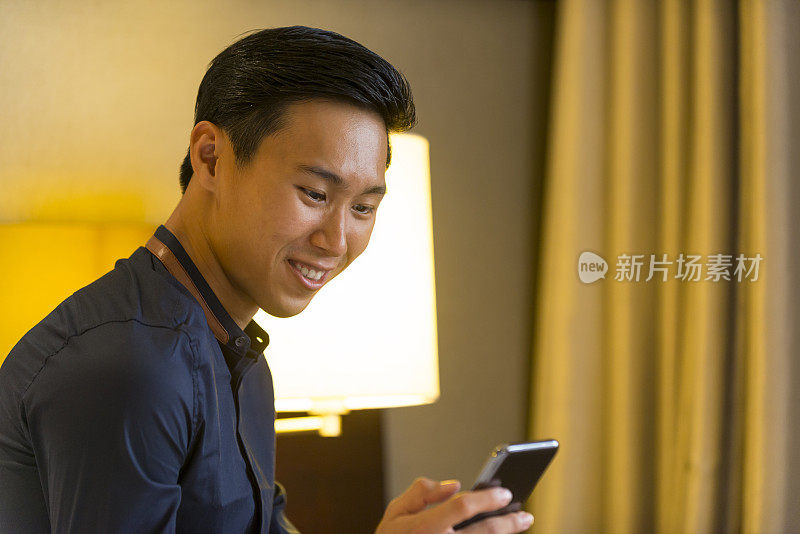 年轻的亚洲商人用智能手机发短信