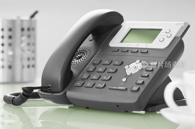 现代化的办公室电话放在绿色的玻璃桌上