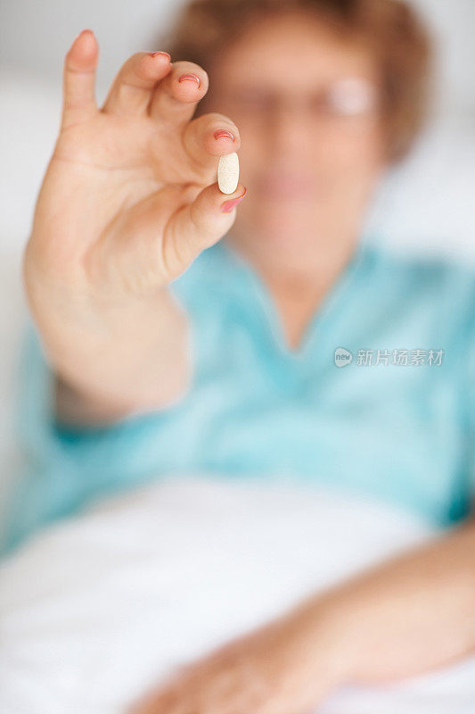 一个拿着药片的女人的特写，专注于药片