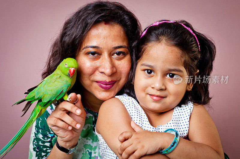印度母亲女儿和绿色鹦鹉坐在她的手上