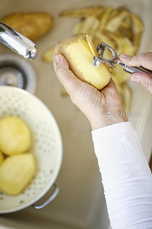 给新鲜的土豆削皮来准备健康的一餐