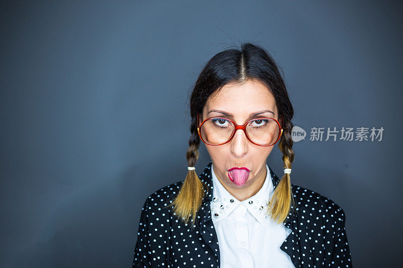 戴着书呆子眼镜的年轻女人吐着舌头