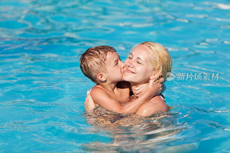 小男孩在游泳池里亲吻他的妈妈