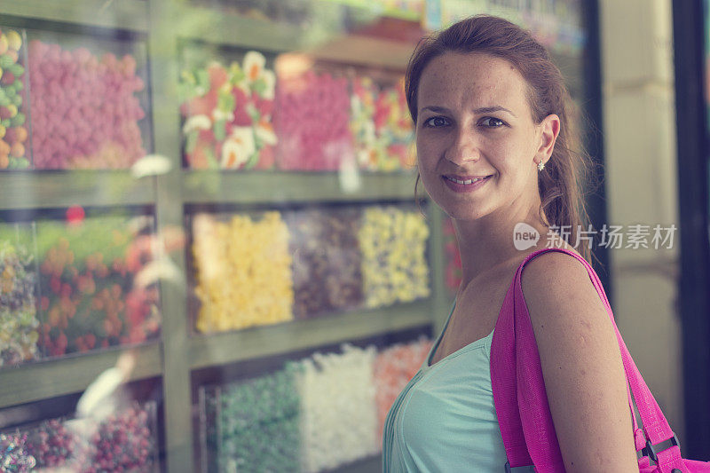 透过商店橱窗欣赏不同糖果的女人