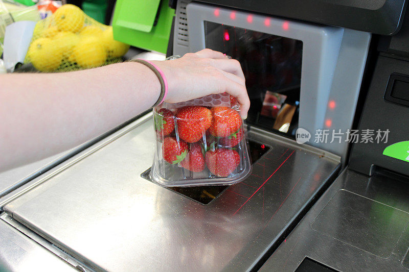 女孩在超市自助结账处扫描购物(草莓)
