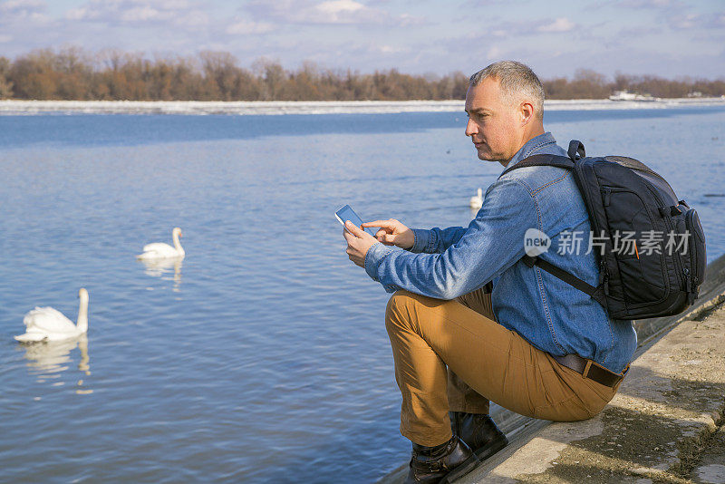一个孤独的男人背着背包坐在河边