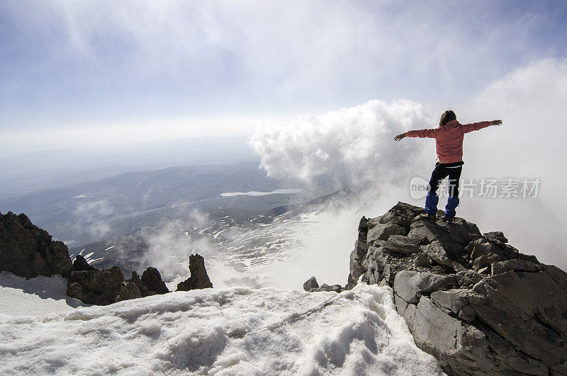 冬天，高山攀登者在山顶张开双臂欣赏美丽的风景