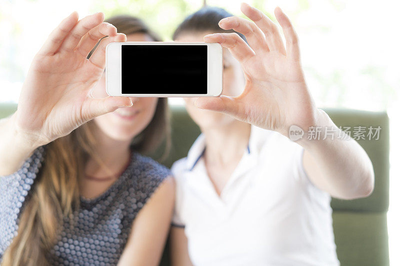两名年轻女子显示智能手机空白