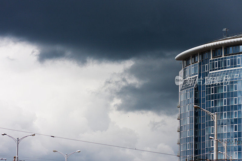 城市前面有一场雷雨，一片乌云密布的天空，一座现代建筑映衬着暴风雨的天空