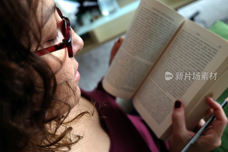 舒适的时刻，在客厅沙发上看书，戴着眼镜和笔