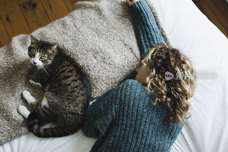 美丽的年轻女子和她的猫在床上