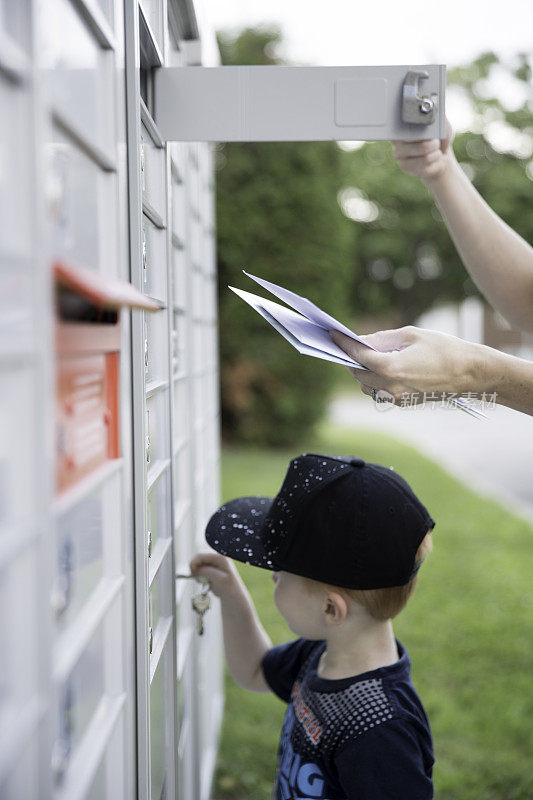一个女人和一个小男孩在邮筒里拿邮件