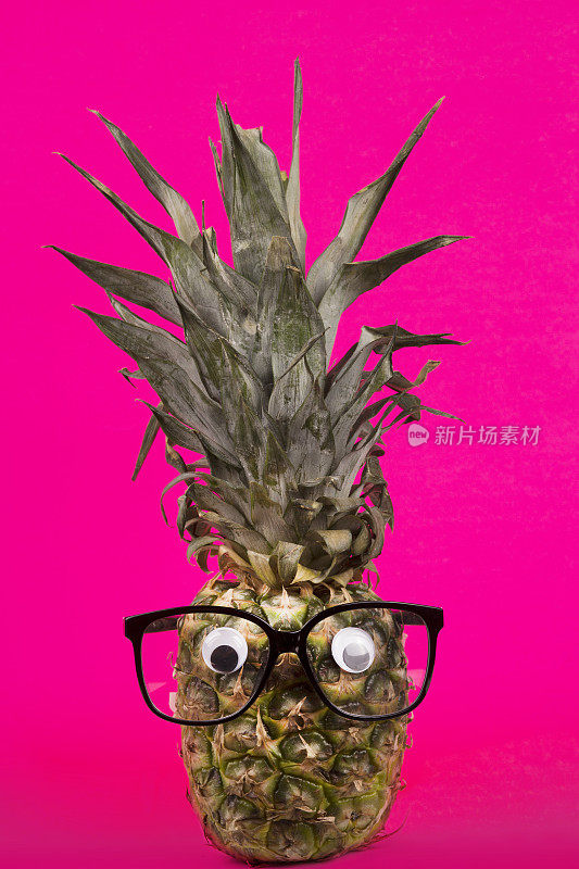 时尚新鲜菠萝与眼镜在粉红色的背景。