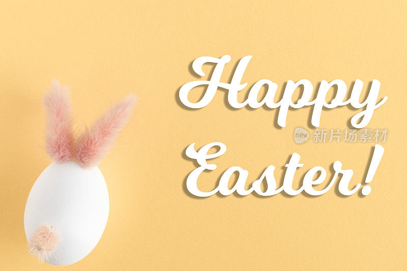 手工制作的复活节彩蛋和兔子在柔和的黄色背景。节日DIY概念与快乐复活节文本