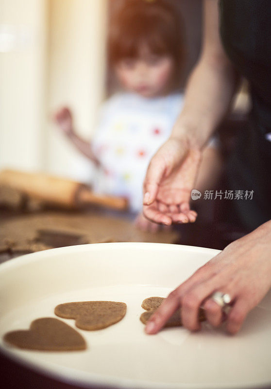 母亲和女儿准备在托盘里烤饼干。