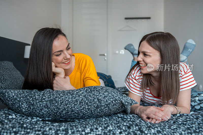 两个女性朋友躺在床上互相聊天