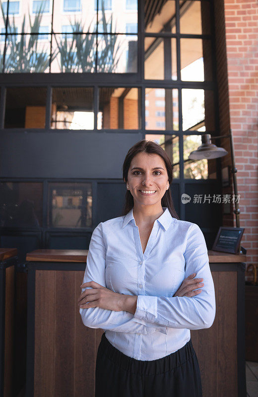 一家豪华酒店的漂亮女主管看着镜头微笑着，双臂交叉