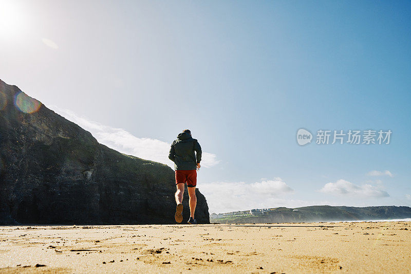 一个阳光明媚的秋日，康沃尔郡，沿着Perranporth海滩跑步的人。