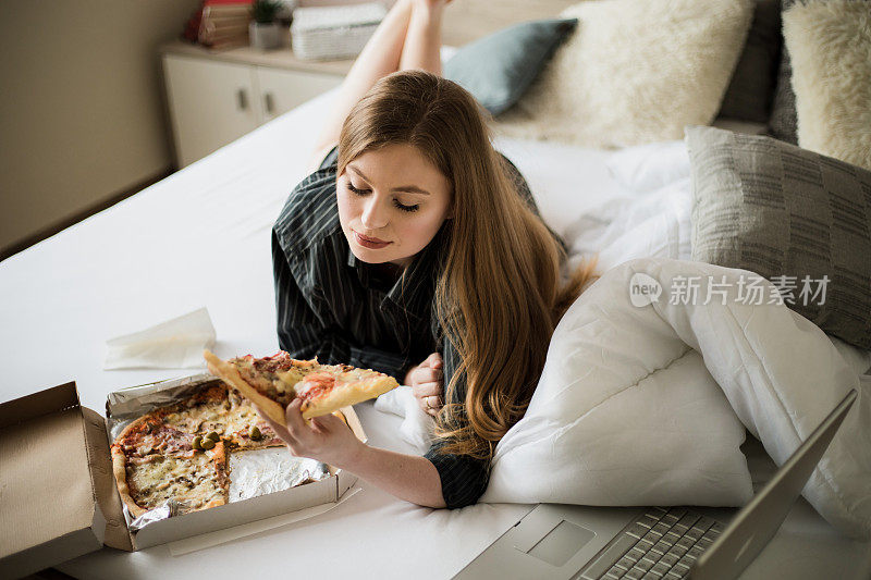 一个小女孩在床上吃披萨