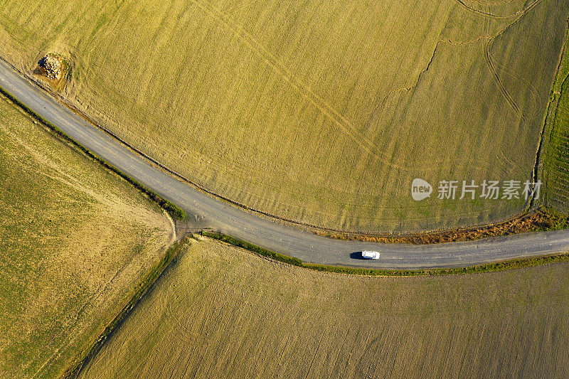 汽车在耕地之间的乡村道路上的鸟瞰图