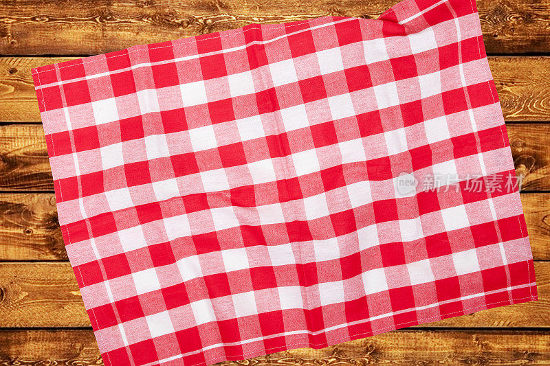 顶视图的一个空的红白格子厨房布，纺织品，桌布或餐巾上模糊的木制背景。模板为您的食品和产品展示蒙太奇。