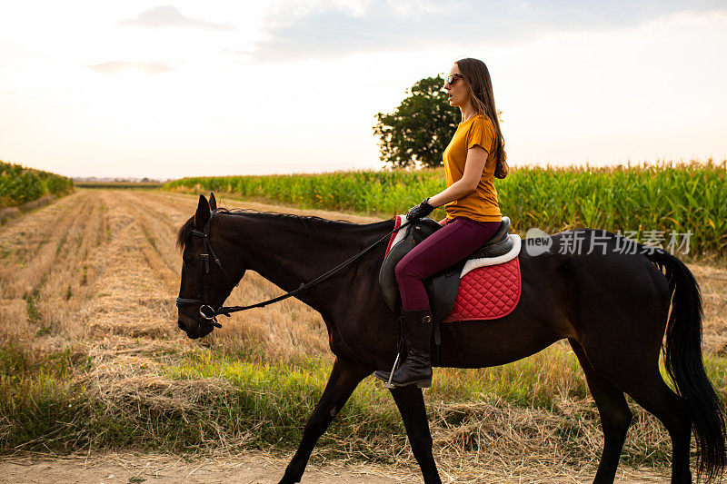 一个年轻的女人骑着马穿过乡村