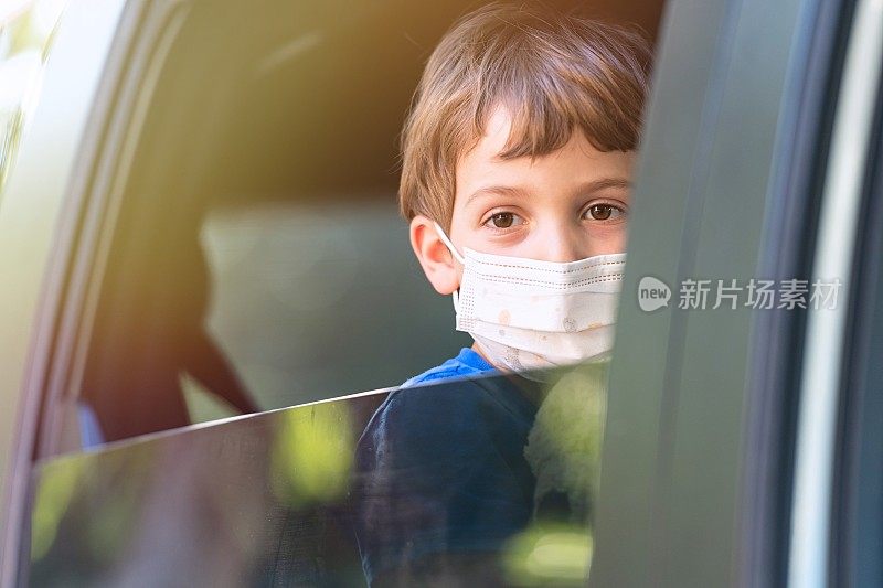 悲伤的小男孩戴着保护面罩看着车窗外的摄像头