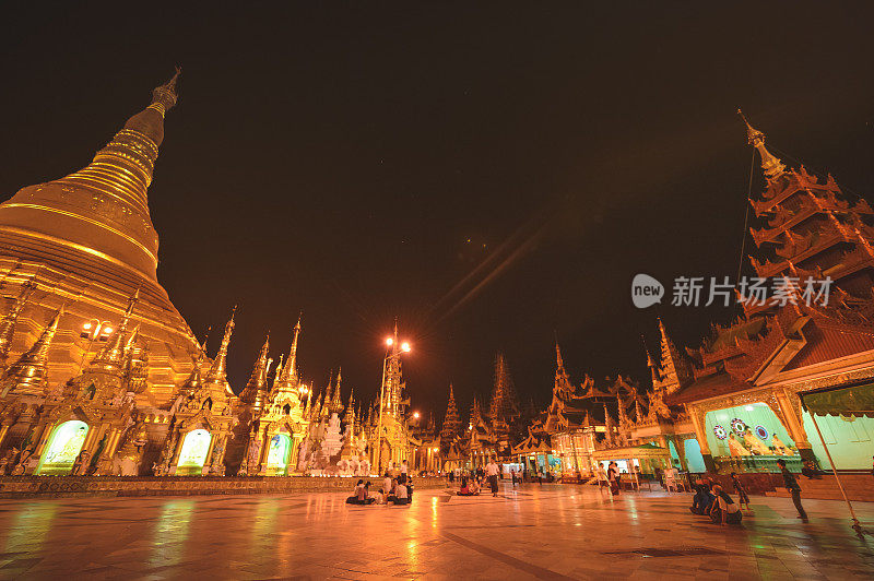 晚上，仰光市中心的大金塔(佛塔)与当地游客和当地人在金塔周围祈祷，亚洲著名的旅游目的地。