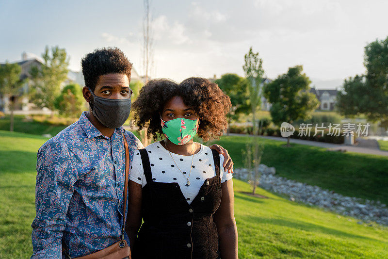 黄昏时分，一对年轻的非洲裔美国夫妇戴着Covid-19防护用品面罩，在户外享受夏季天气，负责任地抚平曲线