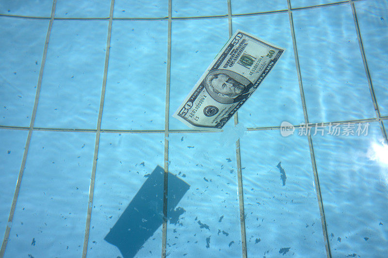 50美元的钞票在清澈的蓝色水面上游泳