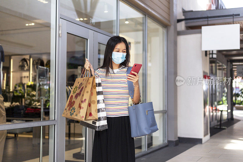 一个女人戴着口罩在购物中心打电话