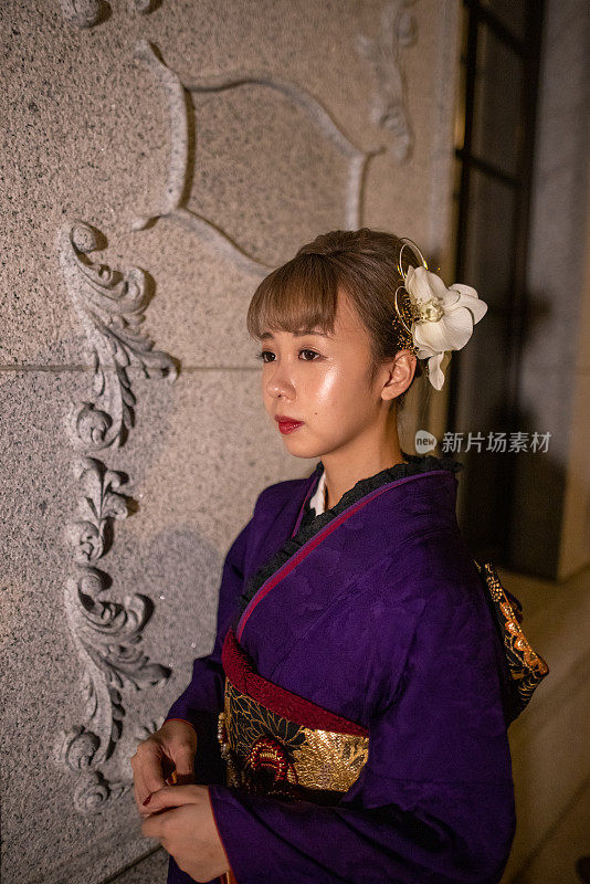 年轻女子的肖像在“Furisode”和服站在白色墙壁在晚上