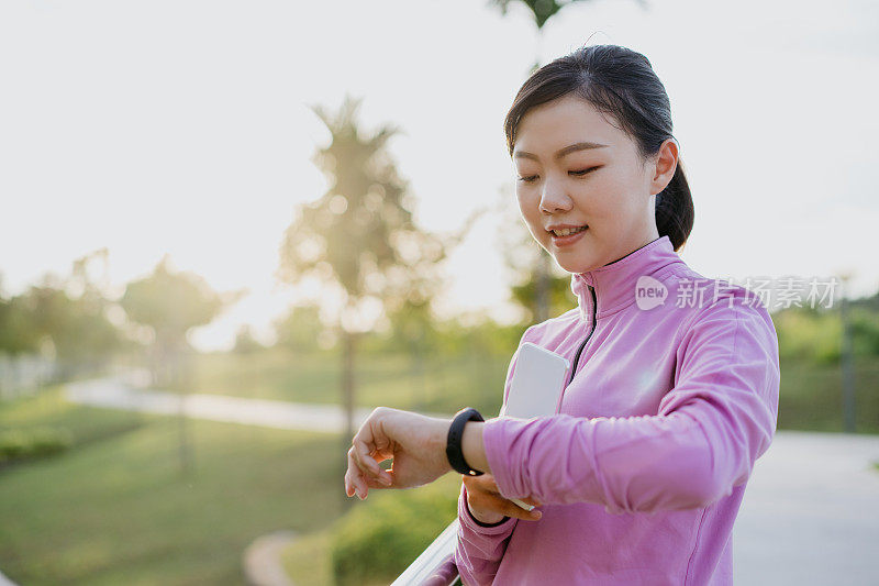 年轻的亚洲女性运动检查她的手腕上的健身追踪器