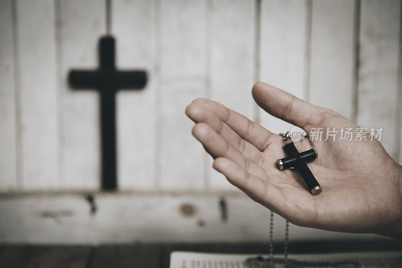 妇女手握木制十字架在教堂祈祷，灵性和宗教。复古的基调。