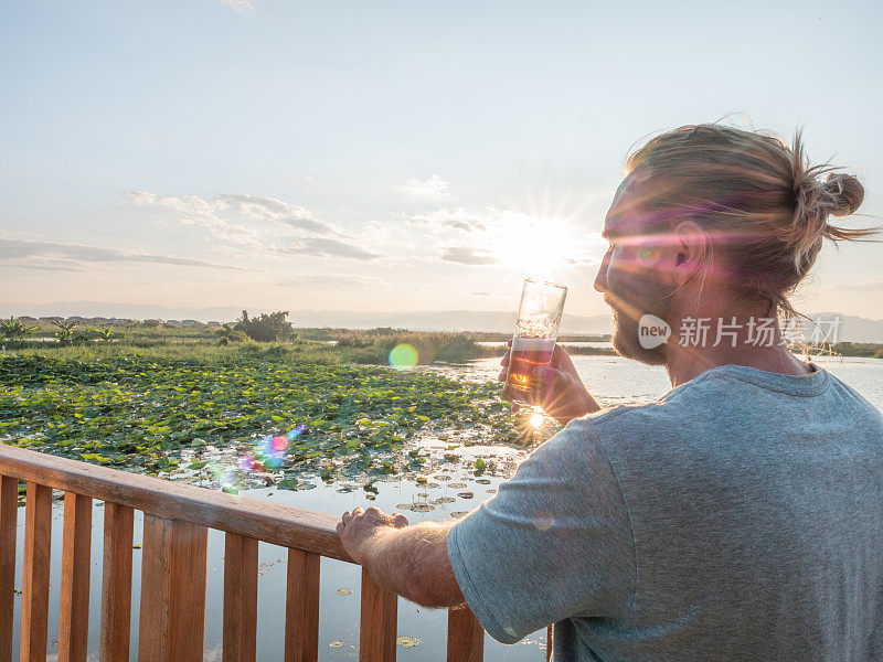 一个男人一边喝着饮料一边看日落