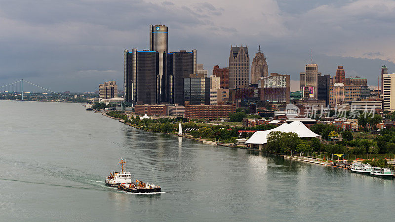 一艘驳船驶过底特律市中心，背景是大使桥