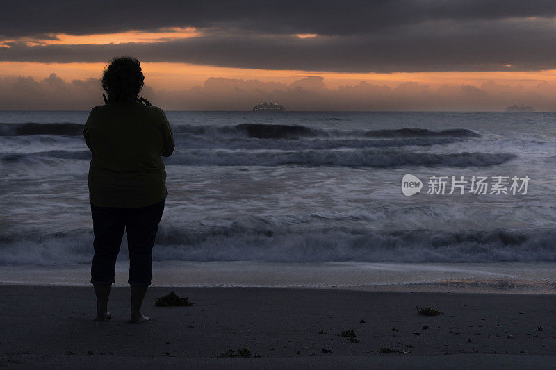 独自的女人欣赏大西洋上的日出