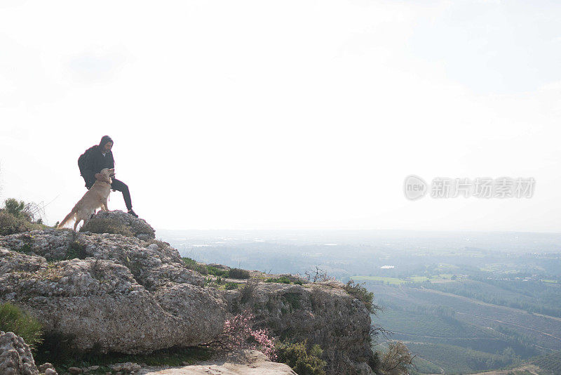 人和狗站在山顶上看山景
