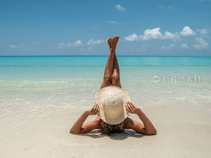 年轻女子在热带海滩上晒太阳，田园诗般的