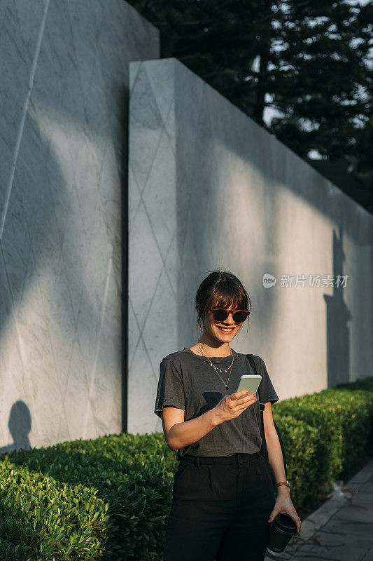 年轻女子站在街上看她的手机(拷贝空间)