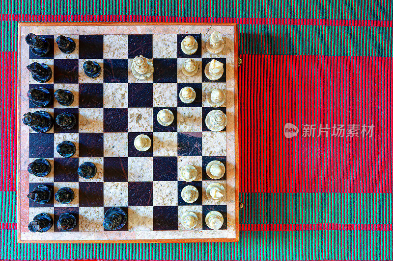 平躺图像显示正在进行的象棋游戏。棋子由石头雕刻而成，棋盘上镶嵌着黑色和浅色的石头