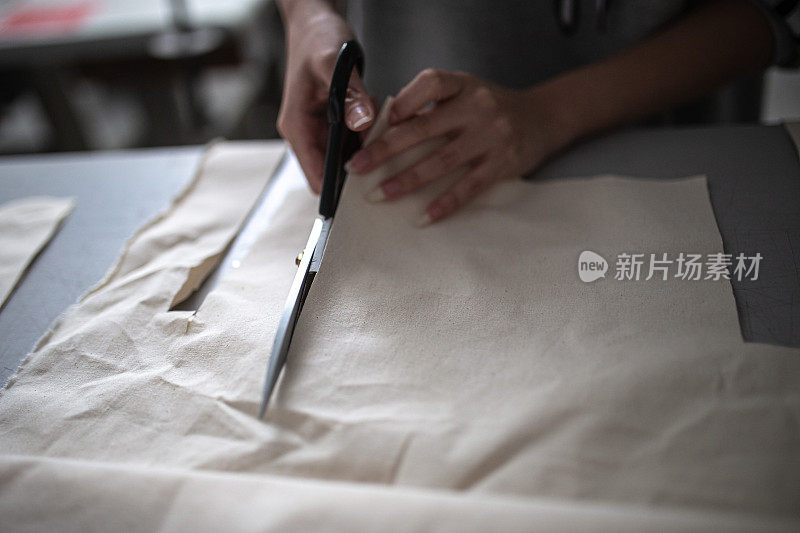 亚洲华裔女性时装大学生在学院工作坊裁剪衬里服装项目