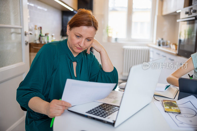 女人在纸上分析数据，她的女儿在网上上课，远程工作和学习