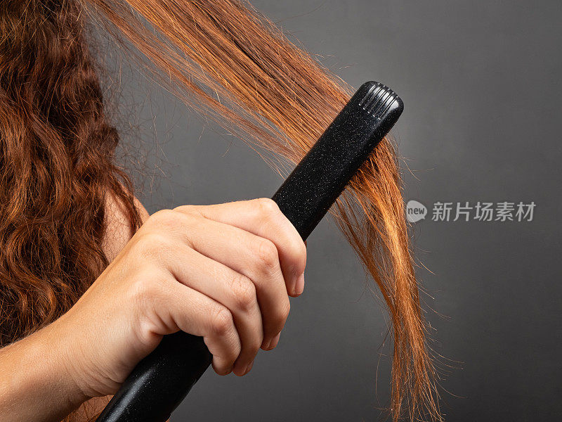 女孩用头发拉直器和卷发器抚平卷发