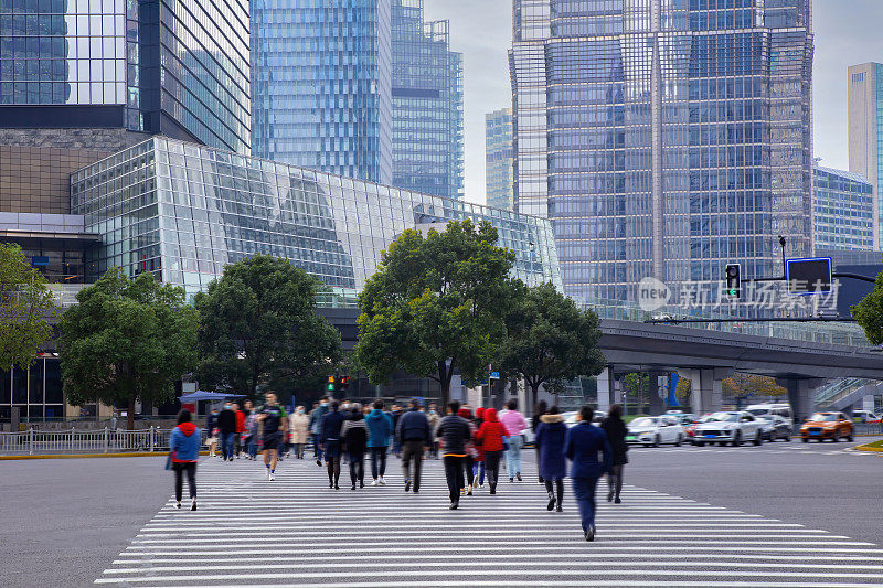 行人走在上海市中心繁忙的十字路口，前面是高楼大厦